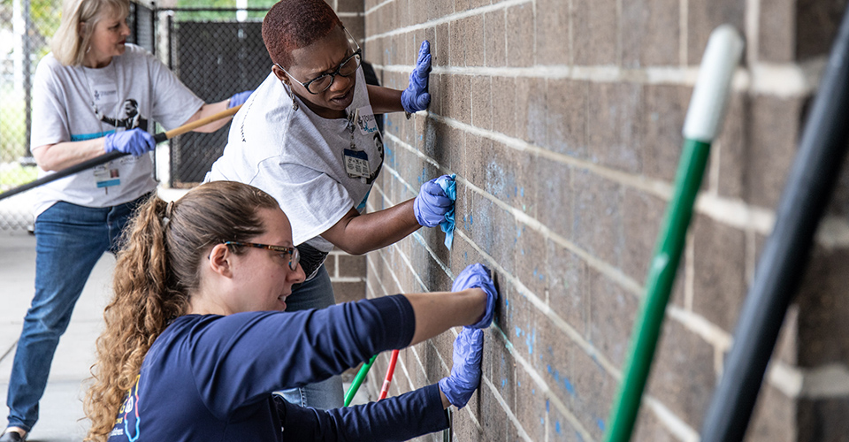 Volunteers clean the outside wall of a building.
