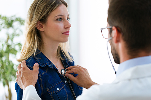 doctor using stethoscope on woman