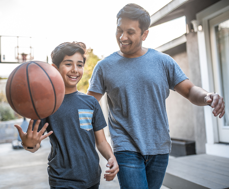 son holding basketball with father
