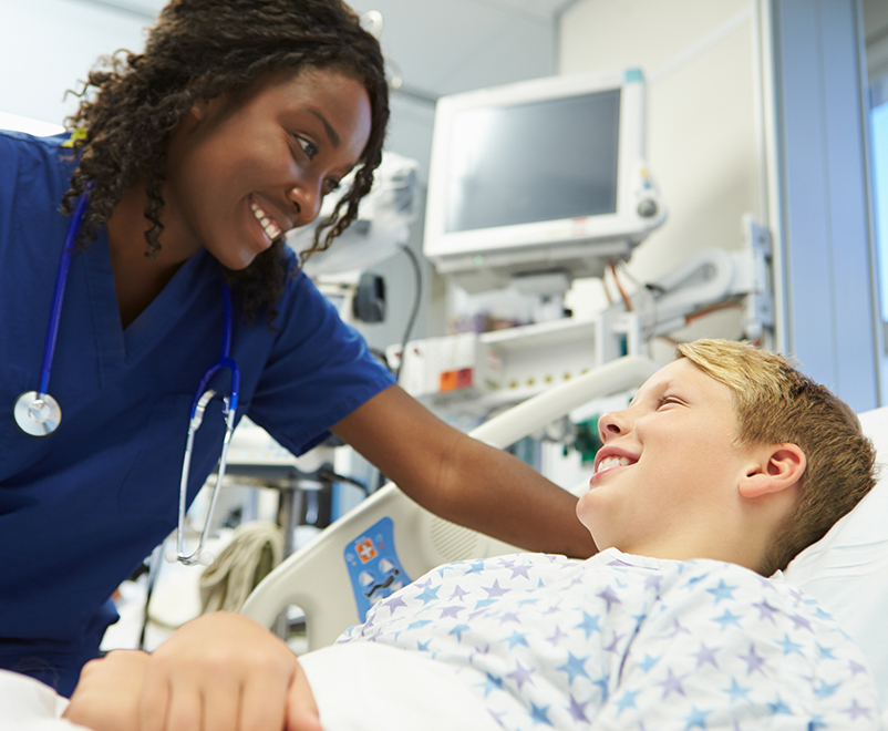 nurse smiling at boy in hospital bed - pediatric cardiac surgery
