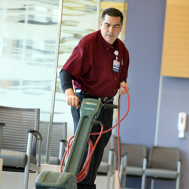 Photo shows Anthony Dominick at work buffing floors.