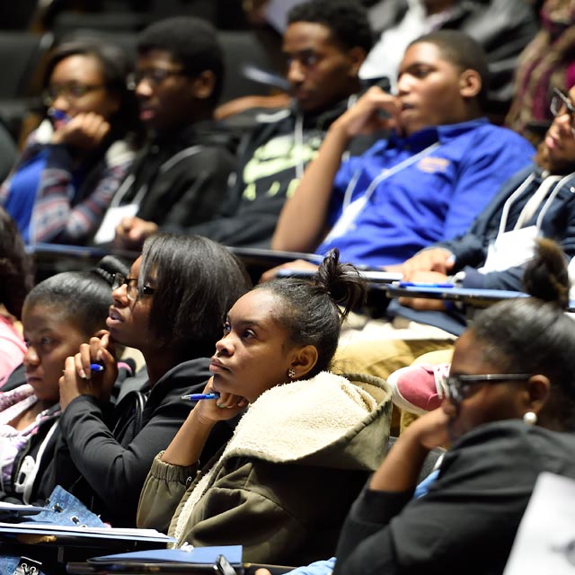 The photo shows students at the Henrietta Lacks Symposium.