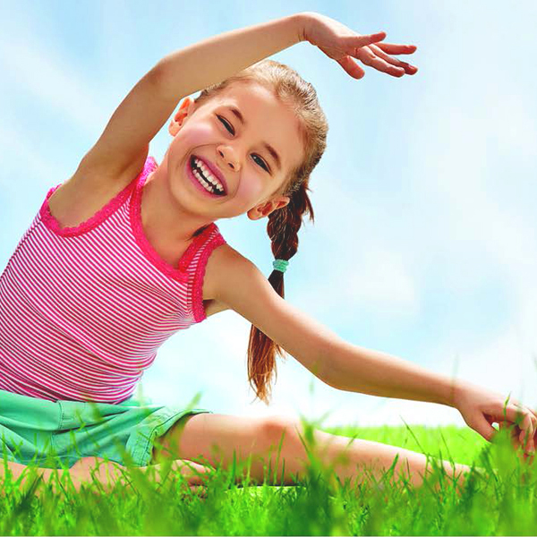 Smiling young girl stretching in the grass on a summer day