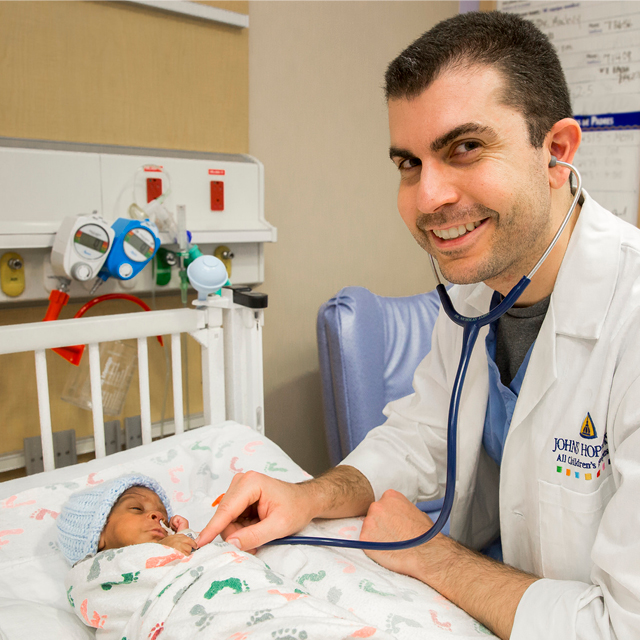 photo of Nick Jabre with a stethoscope, tending to a young patient