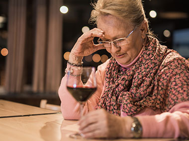woman with pensive expression considering whether to drink a glass of wine