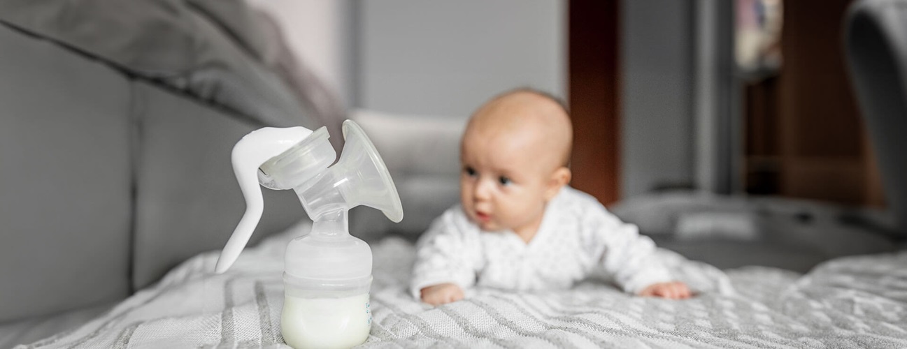 baby looks at breast pump with milk in it