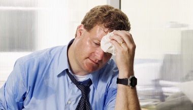 Office worker wiping sweat from his forehead