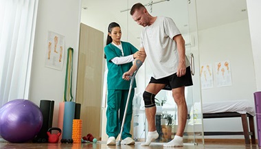 A clinician working with a patient on crutches through therapy and practice walking again.