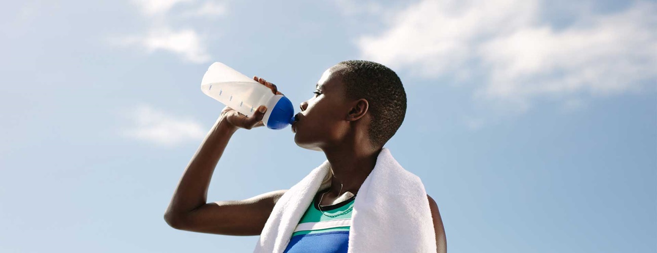 A woman after exercising drinking from a water bottle.