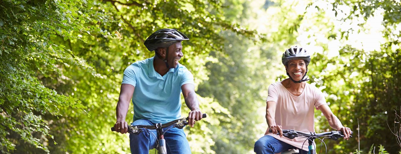 Couple riding bikes together on a wooded path.