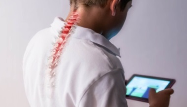 A boy's spine showing strain as he leans forward to play a game on a phone