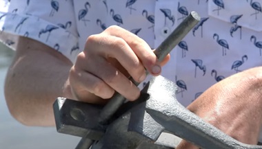 Caleb holding an anchor demonstrating the portion of it that punctured his skull