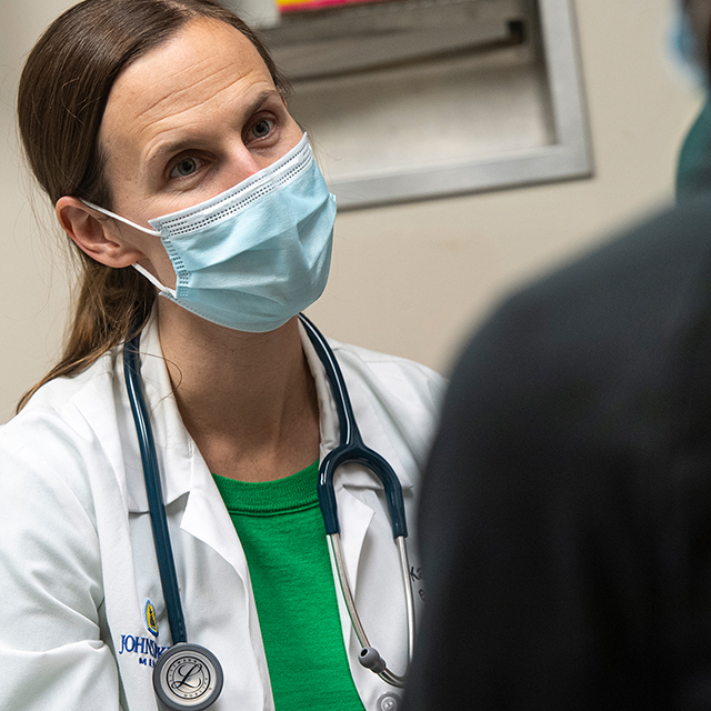 Photo of Katie Shaw wearing a mask and talking to a patient