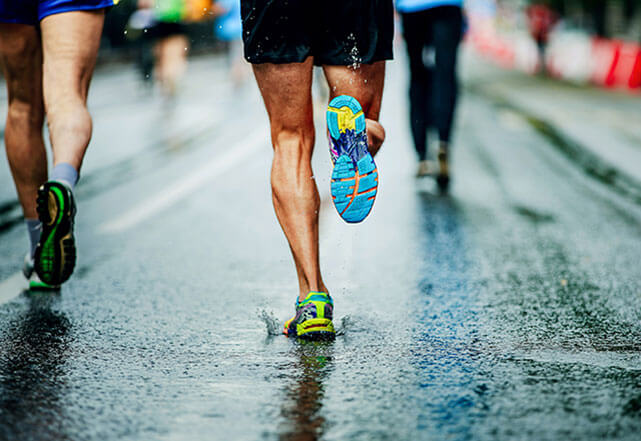 Runners running down wet pavement