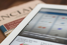 Newspaper and tablet open to financial news.