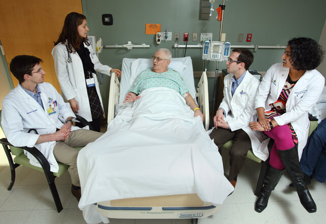 Residents and faculty talking to a patient