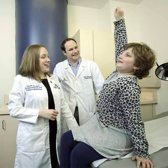 Neurologists Lisa Sun and Ryan Felling standing next to a girl who is recovering from stroke