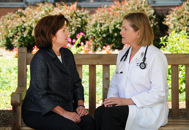 Woman sitting with her doctor sitting outside on bench