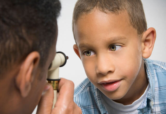A young boy has his eyes checked by a doctor