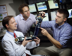 Neurologist Nathan Crone (left) is working with colleagues from the Johns Hopkins Applied Physics Laboratory, including Matthew Johannes (center) and Brock Wester (right), to develop a prosthetic arm using electrical signals from epilepsy patients’ brains