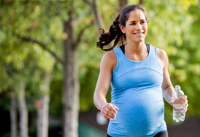 Pregnant woman running and holding a bottle of water.