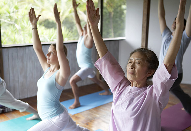 Senior woman demonstrating a yoga position inside a studio. 