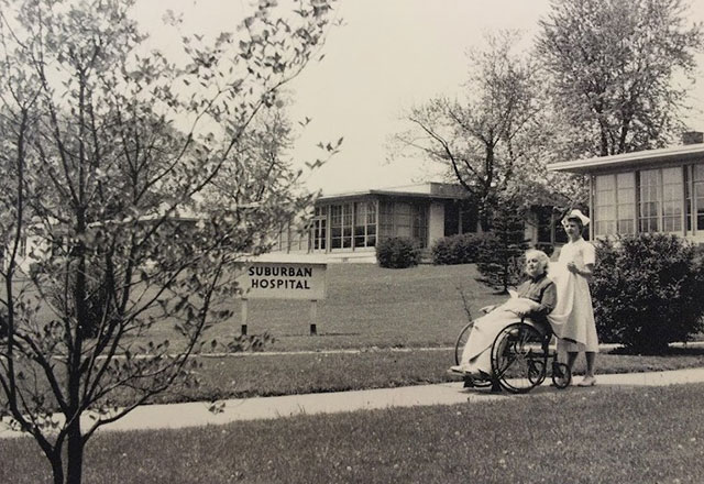 A nurse pushing a patient outside of the original Suburban Hospital