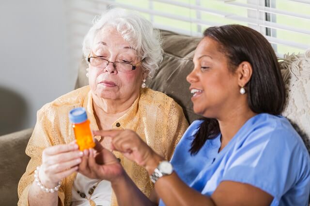 nurse reviewing prescription bottle with patient