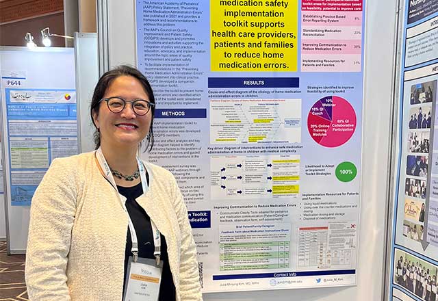 Dr. Julia Kim standing in front of poster presentation at ISQHC