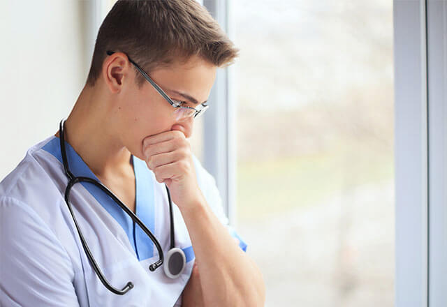 Doctor looking down with hand covering mouth