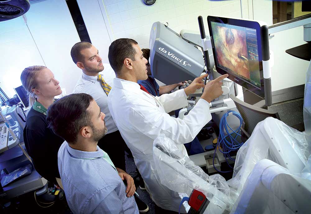 Doctor Ghazi operating a surgical robot and speaking to trainees.