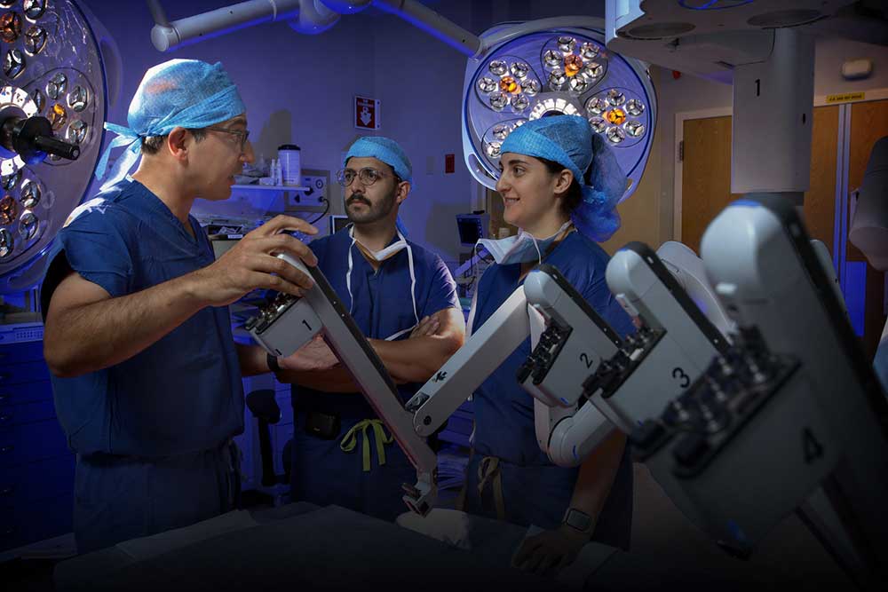 Doctor Allaf operates a surgical robot while two other physicians observe