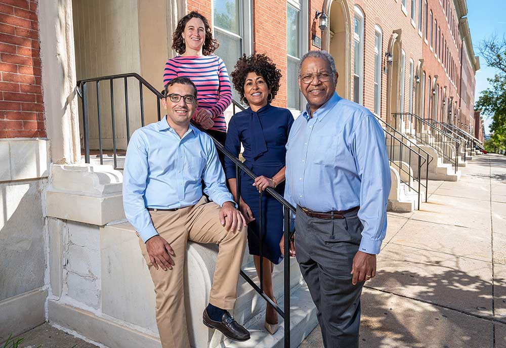 Four researchers smiling together on the front steps of a Baltimore rowhome.
