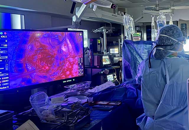 Surgeon looking at a screen that shows red dye highlighting the tumor.