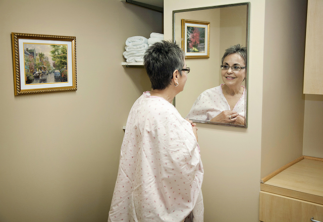 patient wearing hospital gown looks at self in mirror