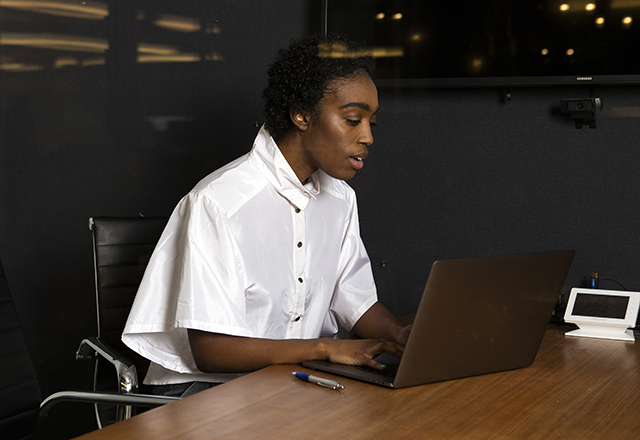 A non-binary person works at a laptop.