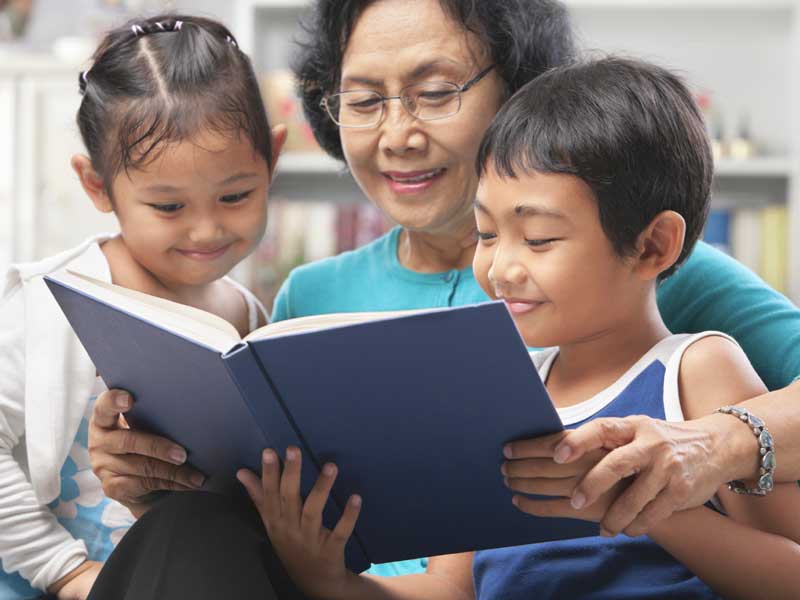 Grandmother reading a book to her grandchildren.