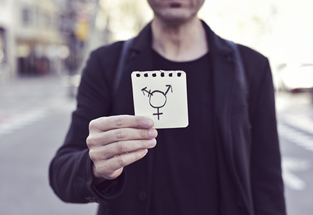 Person holding paper with gender symbols.