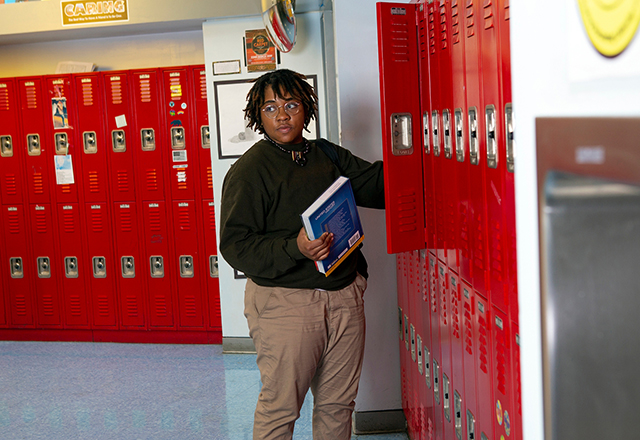 Teen places book in a school locker.