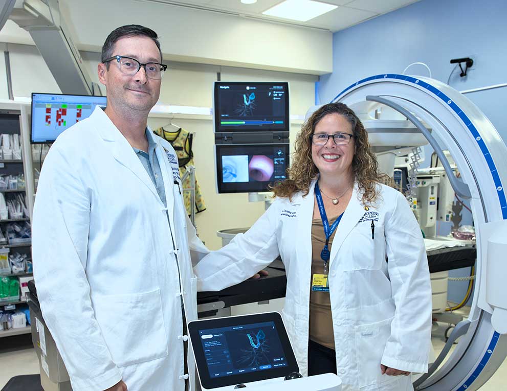 Two doctors standing together smiling in front of imaging equipment