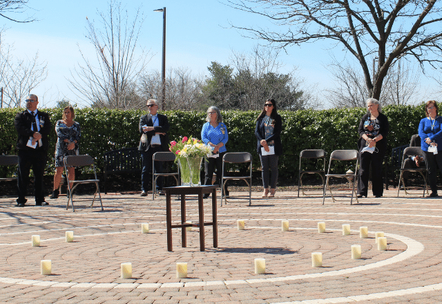 Bayview staff in a circle surrounding candles surrounding flowers