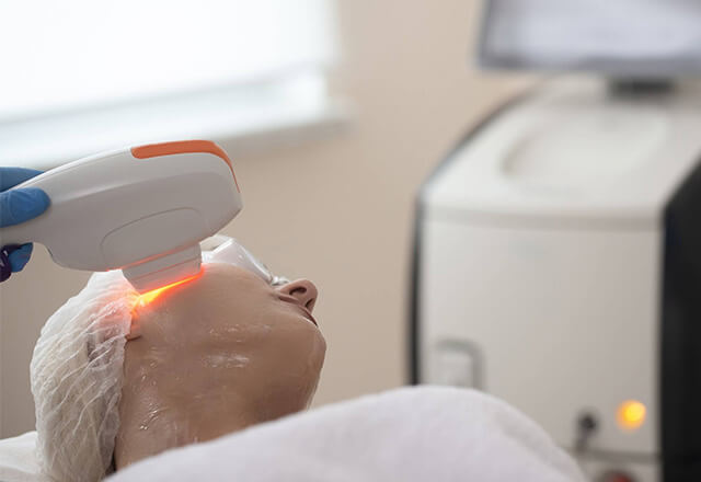 A woman receives laser therapy for facial skin rejuvenation.