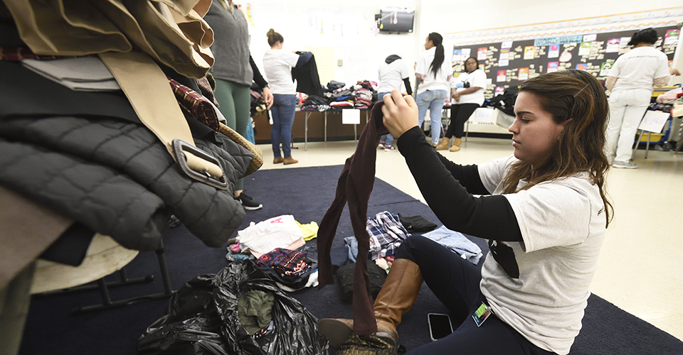 A volunteer sits on the floor, sorting through donations.