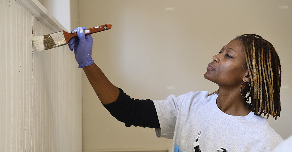 A woman painting a wall with a paintbrush.