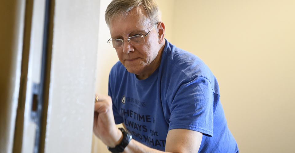 A man concentrates while painting a doorframe.
