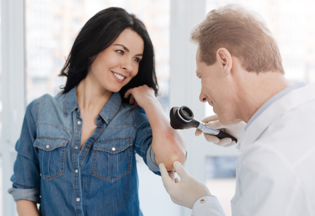 Dermatologist examining a rash on a patients skin
