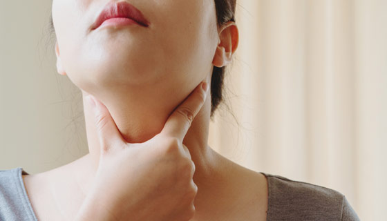 Woman holding neck testing her thyroid gland