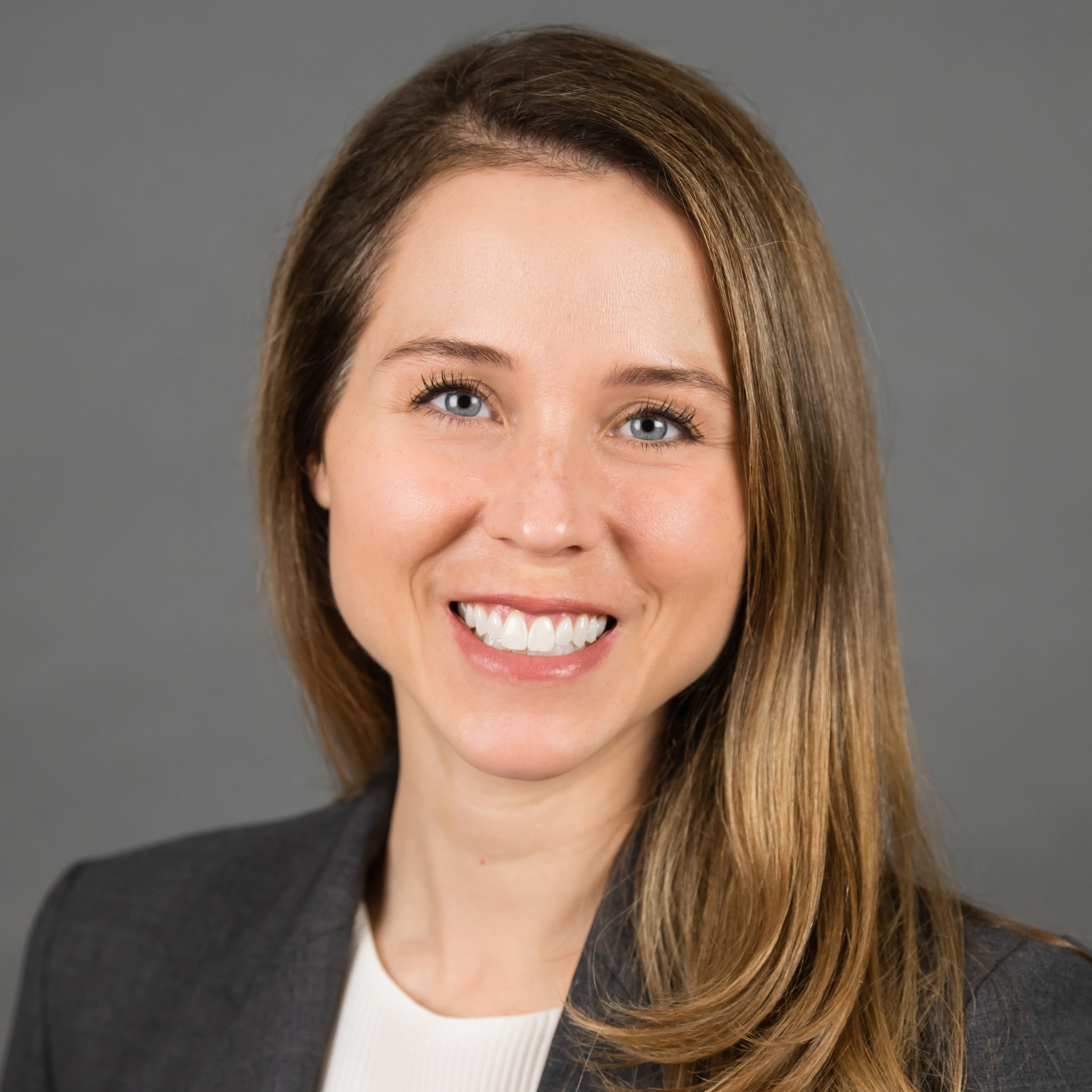 Christine Krueger smiles for a professional headshot in front of a dark gray background.