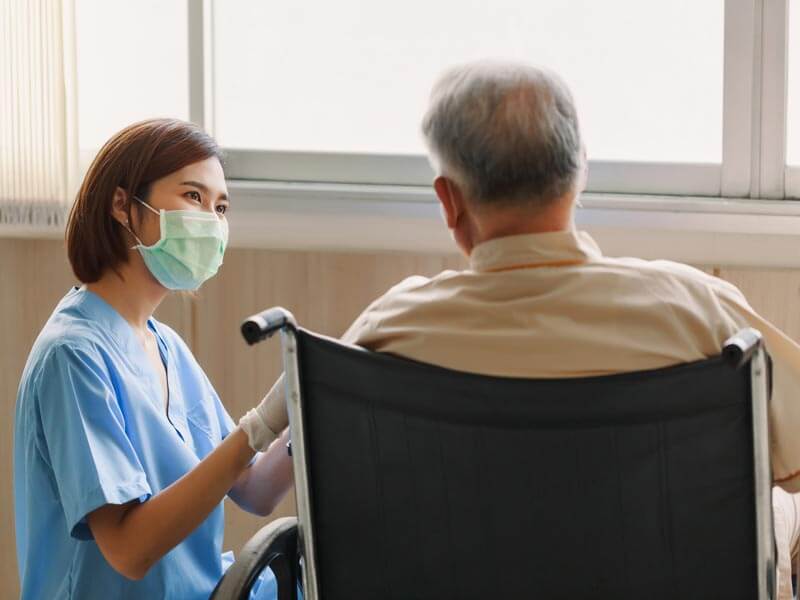 Doctor speaking with elderly patient in wheelchair