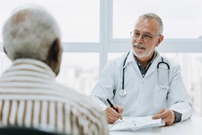 Geriatrician speaks to patient in a bright office